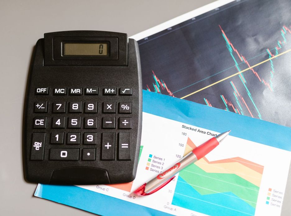 Calculator and pen on a desk with financial charts