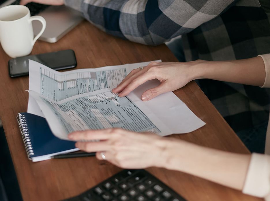 Hands sorting tax forms on a wooden desk