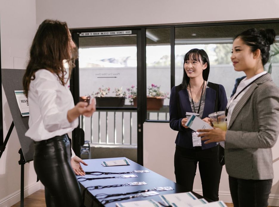 Businesswomen registering at a conference desk, smiling and interacting in a professional setting