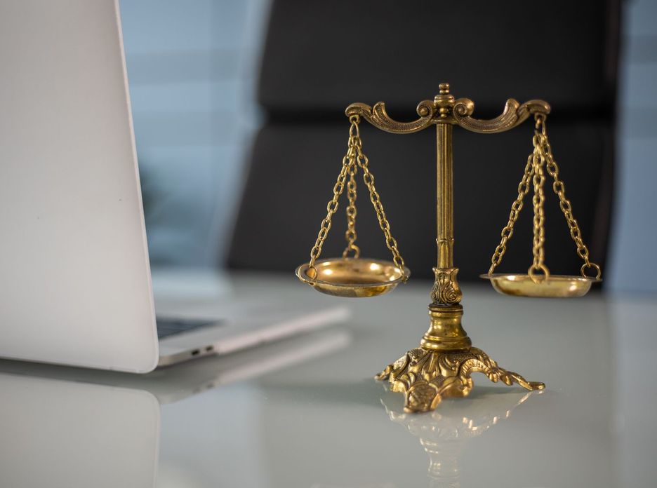 Golden justice scales on a desk beside a laptop