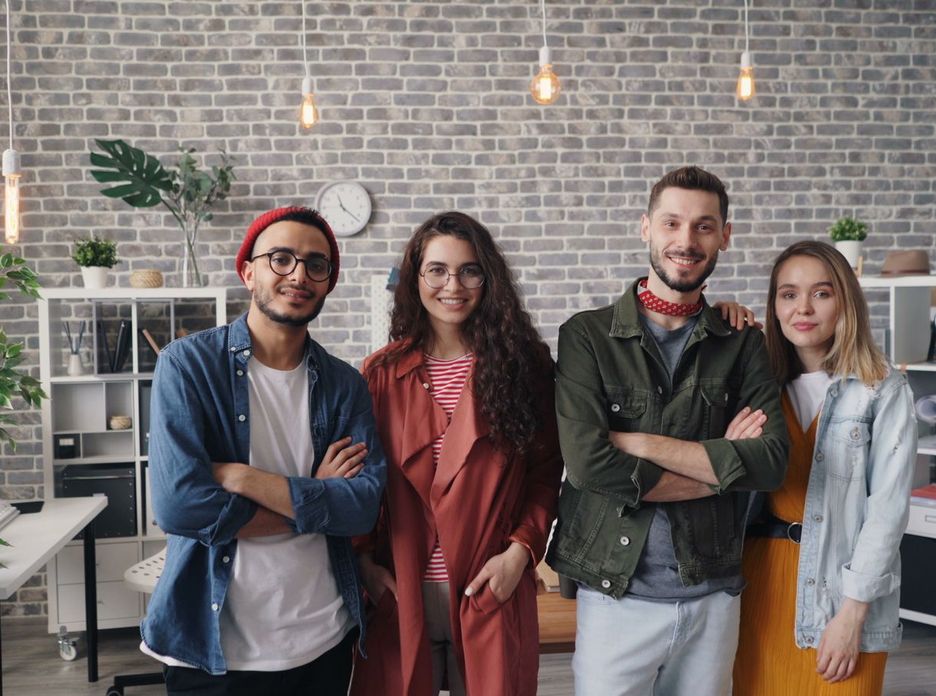 A cheerful group of young professionals smiling confidently in a modern office setting