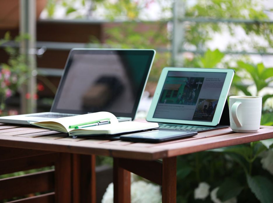A laptop and a tablet side by side on a wooden table