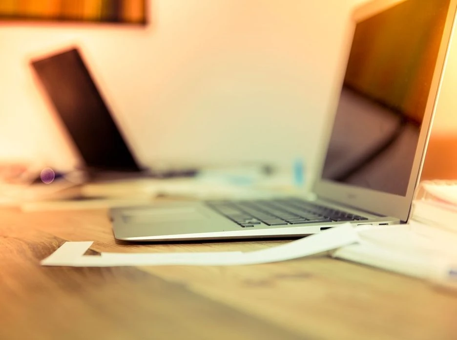 Two laptops on a wooden desk in warm light