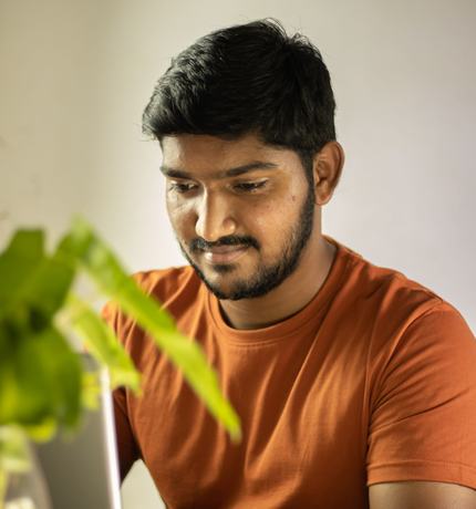 A man in an orange shirt working on his laptop