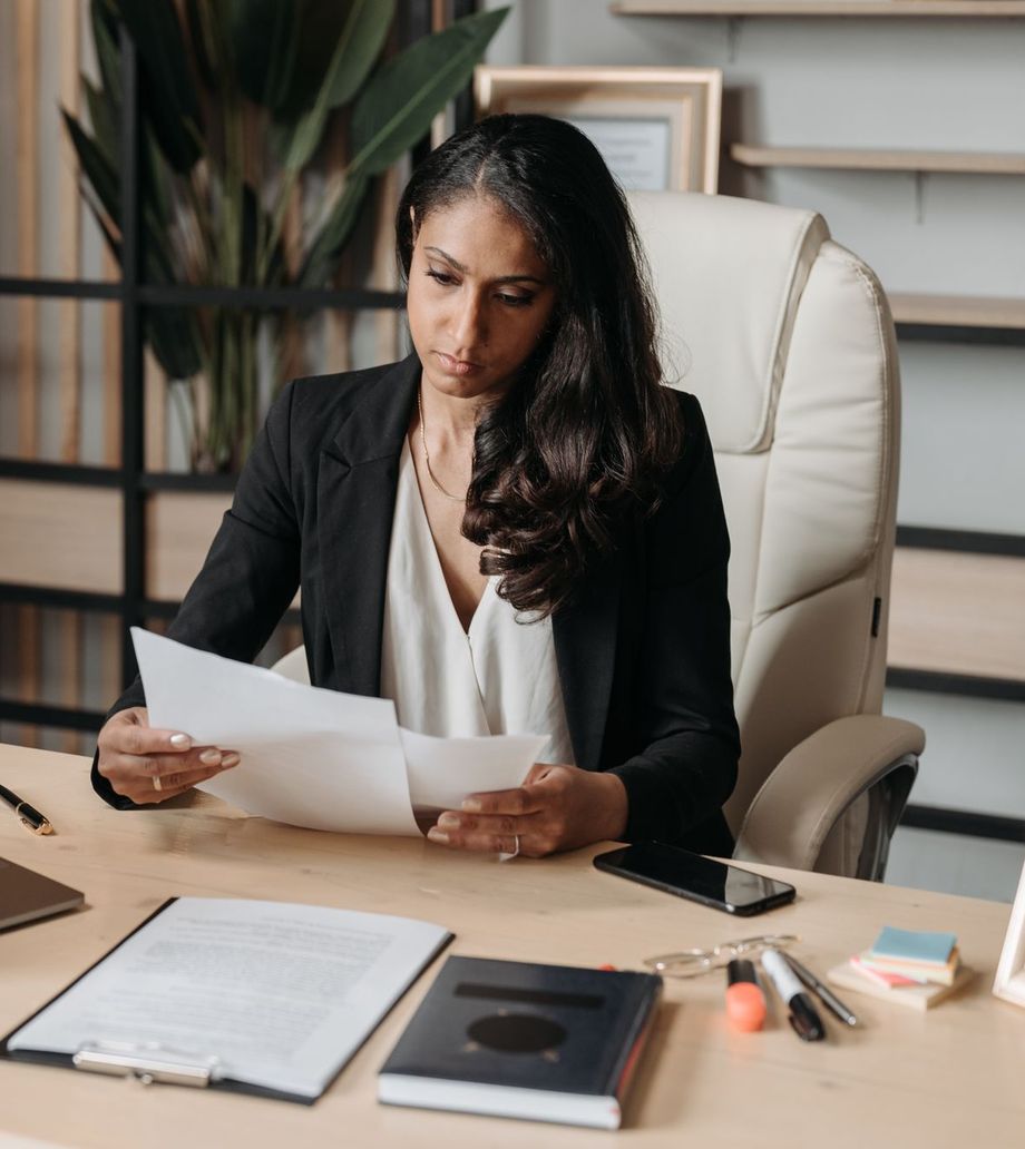An accountant reading a document at her desk, laptop open beside her
