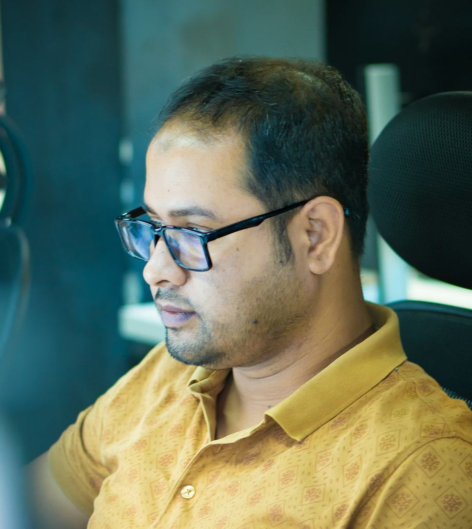 A man in glasses and a mustard shirt working at his computer